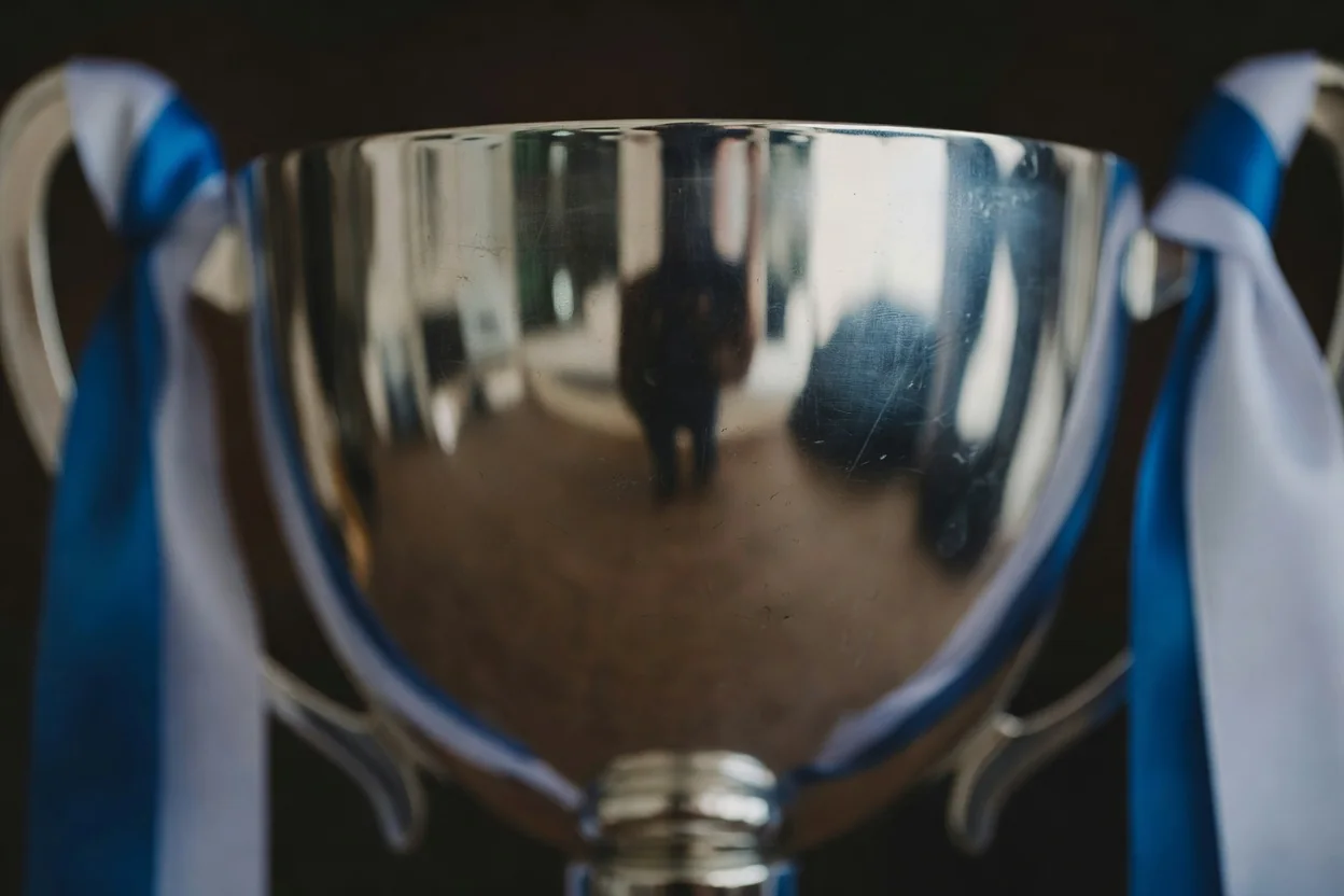 Superfície brilhante de troféu refletindo fitas azuis e brancas.